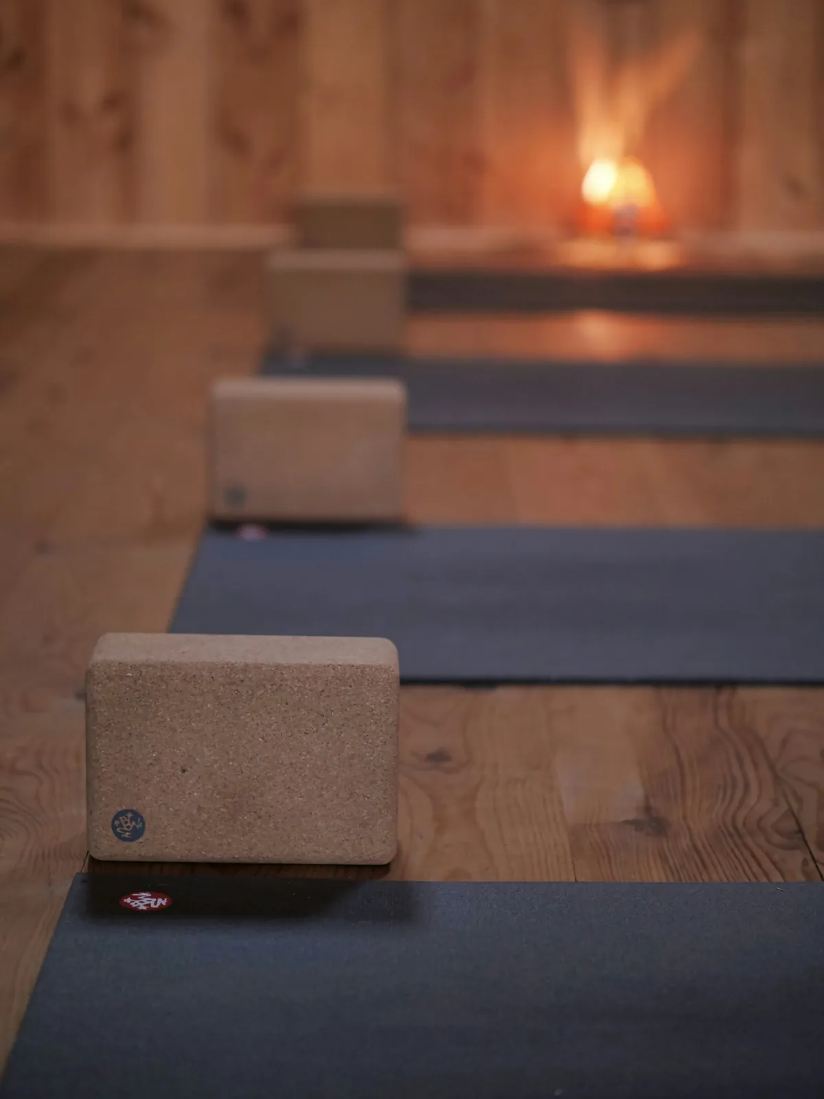 Rows of mats and cork blocks in the studio with a candle glowing at the far end