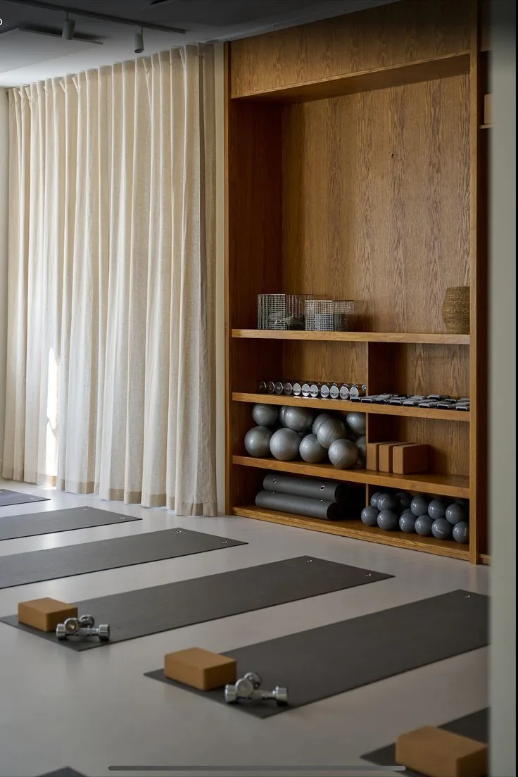 Studio shelves with mats, blocks and weights beside a curtained window